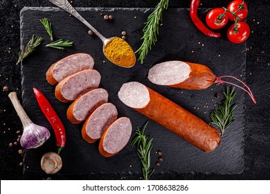 Various Sausages And Smoked Products Lie On A Black Board, Sausage, Sausages, Ribs, Rolls. Top View, Overhead. Flat Lay