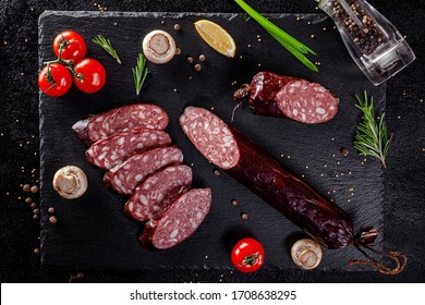 Various Sausages And Smoked Products Lie On A Black Board, Sausage, Sausages, Ribs, Rolls. Top View, Overhead. Flat Lay