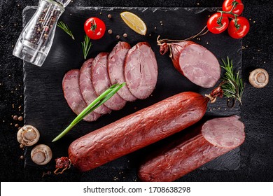 Various Sausages And Smoked Products Lie On A Black Board, Sausage, Sausages, Ribs, Rolls. Top View, Overhead. Flat Lay