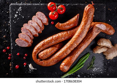 Various Sausages And Smoked Products Lie On A Black Board, Sausage, Sausages, Ribs, Rolls. Top View, Overhead. Flat Lay