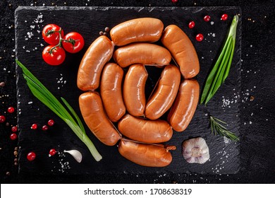 Various Sausages And Smoked Products Lie On A Black Board, Sausage, Sausages, Ribs, Rolls. Top View, Overhead. Flat Lay