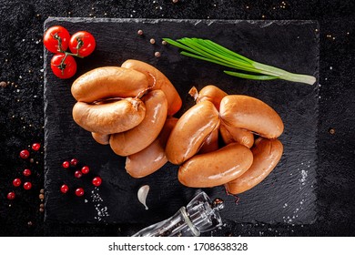 Various Sausages And Smoked Products Lie On A Black Board, Sausage, Sausages, Ribs, Rolls. Top View, Overhead. Flat Lay