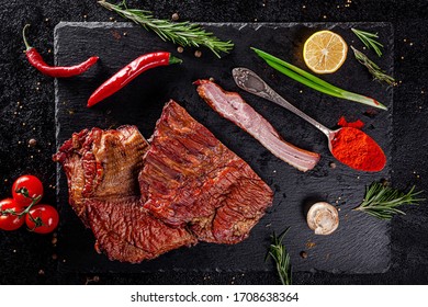 Various Sausages And Smoked Products Lie On A Black Board, Sausage, Sausages, Ribs, Rolls. Top View, Overhead. Flat Lay