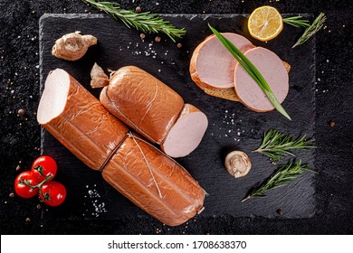 Various Sausages And Smoked Products Lie On A Black Board, Sausage, Sausages, Ribs, Rolls. Top View, Overhead. Flat Lay