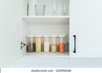 Various Seeds In Storage Jars In Pantry, White Modern Kitchen In Background. Smart Kitchen Organization. Healthy Cooking, Clean Eating Concept. Balanced Dieting Food.