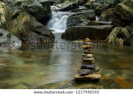 Various shaped stacked Zen stones against a waterfall background