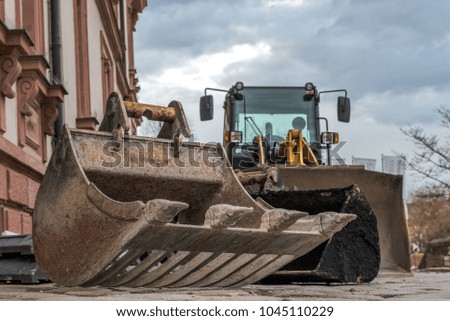 Various shovels lie in front of a bolldozer in a construction site. Concept: craft or construction site