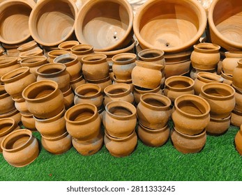 Various sizes of empty handmade earthen pottery and terracotta planters arranged for sale at a market.