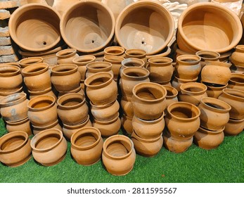 Various sizes of empty handmade earthen pottery and terracotta planters arranged for sale at a market.