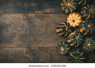 Various small pumpkins with a striped pattern on wooden background, top view with copy space - Shutterstock ID 2382391581