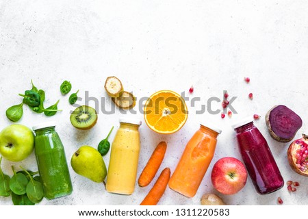 Various smoothies or juices in bottles and ingredients on white, healthy diet detox vegan clean food concept, top view, copy space.