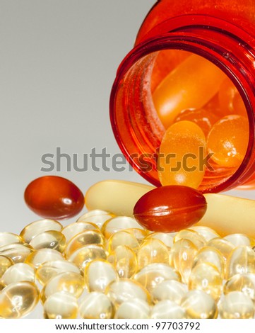 Various sorts of fish oil tablets spilling from prescription bottle onto table