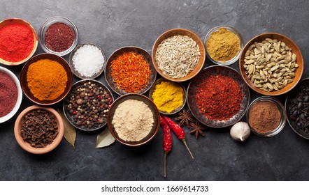 Various spices in bowls on dark stone table. Indian cuisine. Top view flat lay