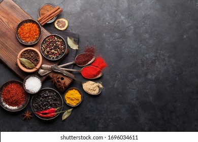 Various spices in bowls and spoons on dark stone table. Indian cuisine. Top view flat lay with copy space