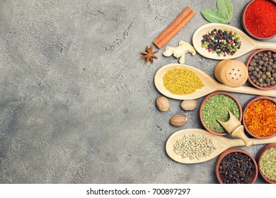 Various spices and herbs in wooden utensils on the concrete background. - Shutterstock ID 700897297