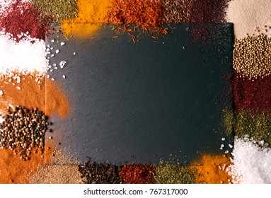 Various spices on black slate stone shot from aerial view. Frame composition of spices on dark cutting board with copy space, top view, close-up