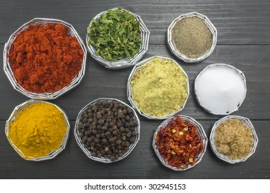 Various spices in shiny bowls on a dark wooden table - Shutterstock ID 302945153