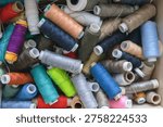 Various spools of multicolored sewing thread filling a box, creating a textile background for craft and fashion concepts