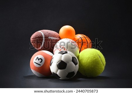 Various sports concept with stack of different balls on black isolated background. Front view.