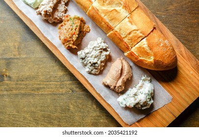 Various spreads on bread and fresh baguette on a wooden table. Hearty breakfast. Blurred and selective focus