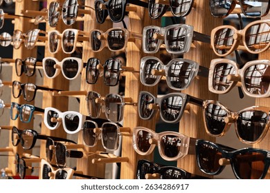 Various stylish sunglasses with different frames are displayed on a wooden rack, reflecting light and creating a vibrant summer mood.