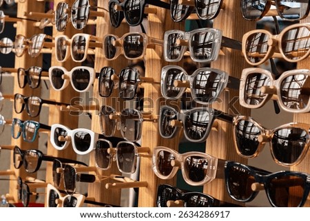 Various stylish sunglasses with different frames are displayed on a wooden rack, reflecting light and creating a vibrant summer mood.
