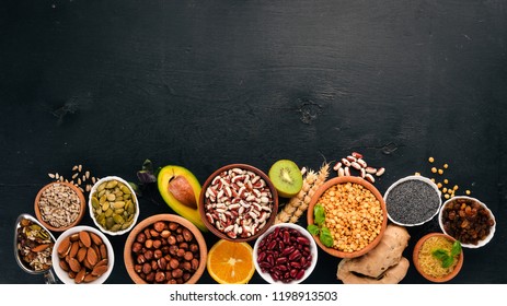 Various superfoods. Dried fruits, nuts, beans, fruits and vegetables. On a black wooden background. Top view. Free copy space. - Shutterstock ID 1198913503