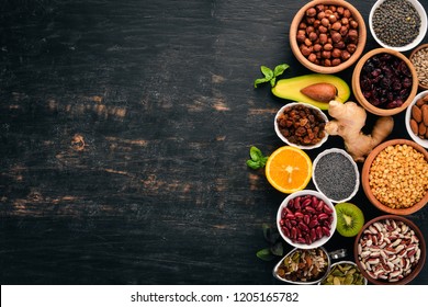 Various superfoods. Dried fruits, nuts, beans, fruits and vegetables. On a black wooden background. Top view. Free copy space.