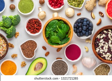 various superfoods on white marble background. vegetables, matcha, acai, turmeric, fruits, berries, avocado, mushrooms, nuts and seeds. healthy vegan food top view