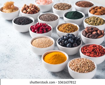 Various superfoods in smal bowl gray concrete background. Superfood as chia, spirulina, raw cocoa bean, goji, hemp, quinoa, bee pollen, black sesame, turmeric. Copy space for text.
