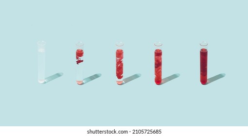 Various Test Tubes With Blood Dissolving On A Pastel Blue Background. Bio Weapon Research Minimal Concept.