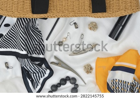 Various things that fell out of a woman's wicker handbag: jewelry, hair clip, headscarf, earrings, mirror, bracelet and empty space on the right side.