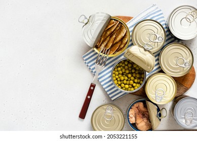 Various Tin Cans For Food Preservation On Gray Concrete Background Top View. Different Canned Food In Steel Cans. Conservation Food, Donation Concept.