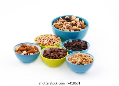 Various Trail Mix Ingredients In Little Green And Blue Bowls