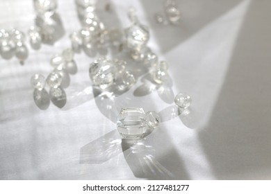 Various transparent beads on white background, illuminated by sunlight and reflectiing light. Selective focus. - Shutterstock ID 2127481277