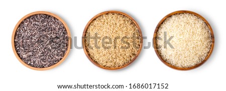 Various type and color of rice ;  riceberry, brown coarse rice and white thai jasmine rice in wooden bowl isolated on white background. Healthy food concept. Flat lay. Top view.