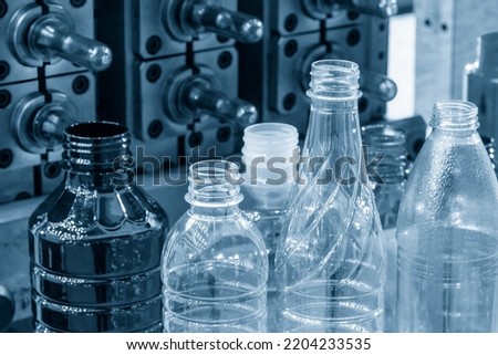 The various type of plastic bottles with injection mold background. The hi-technology of drinking water manufacturing process concept.