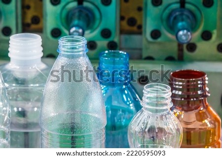 The various type of plastic bottles with injection mold background. The hi-technology of drinking water manufacturing process concept.