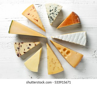 Various Types Of Cheese On White Wooden Table, Top View