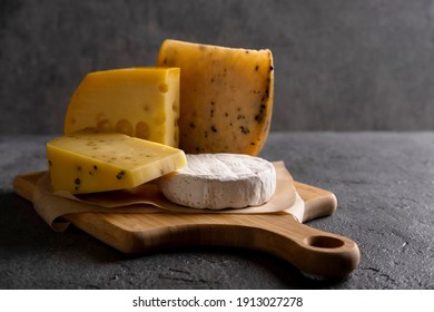 Various types of cheese on wooden board. Free space for your text. Dark moody.