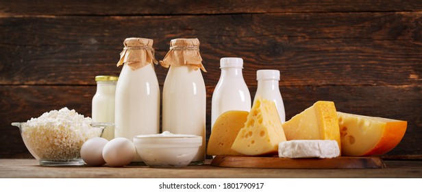 Various types of dairy products : milk, cheese, cottage cheese, eggs, yogurt on a wooden background - Shutterstock ID 1801790917
