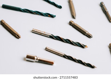 Various types of drill bits and screwdriver bits arranged on a flat surface for different uses