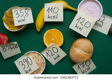 various types of food with labels informing about the amount of calories. Taking care of your diet and calorie intake. Flat lay photo on a green background - Shutterstock ID 2365383771
