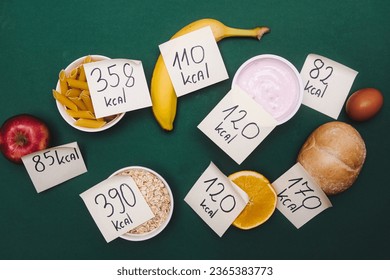 various types of food with labels informing about the amount of calories. Taking care of your diet and calorie intake. Flat lay photo on a green background - Shutterstock ID 2365383773