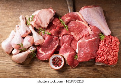 various types of fresh meat: pork, beef, turkey and chicken on a wooden table, top view - Shutterstock ID 1619708218