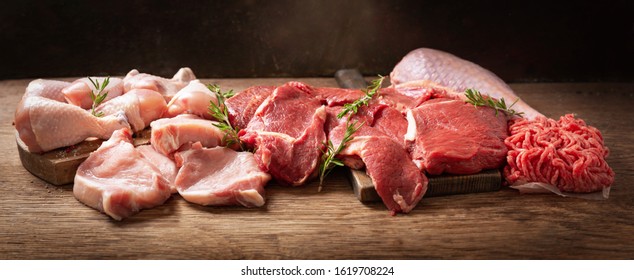 various types of fresh meat: pork, beef, turkey and chicken on a wooden table