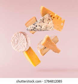 Various types of fresh tasty cheese fall in the air isolated on pink background . Food levitation concept, high quality image