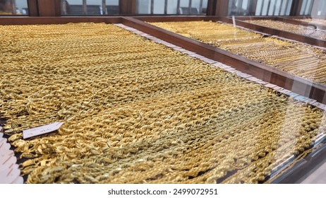 various types of gold necklace jewelry in a gold shop in a glass table display - Powered by Shutterstock