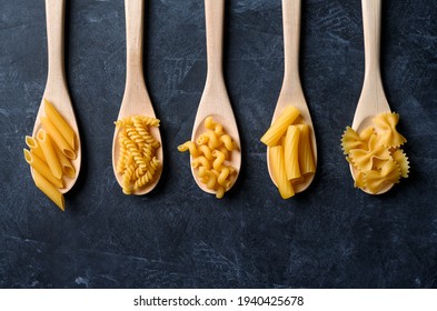 Various types of pasta on black background. Pasta in wooden spoons. - Powered by Shutterstock