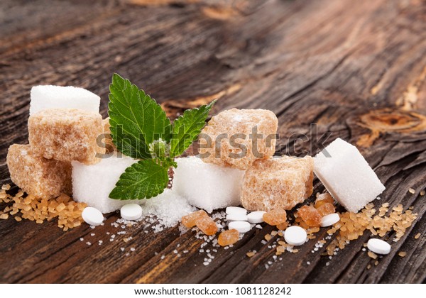Various types of sugar and artificial sweetener on\
nwooden table.
